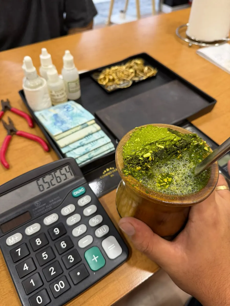 Mesa de avaliação com calculadora, peças de ouro e chimarrão